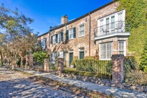 Exterior shot of historically significant brick row houses on a cobblestone street in Charleston, SC