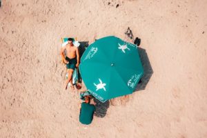Man lying on the beach beside an Isle of Palms sun umbrella
