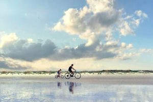 Father and son biking across a beach in Charleston, SC