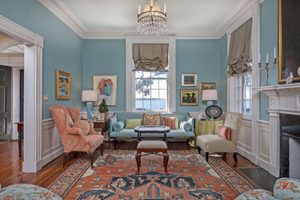 Charleston historic house interior. Living room with blue walls, white trim, antique furniture, and crystal chandelier. 