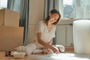 Woman sitting on the floor cutting pieces of bubble wrap to pack antique furniture