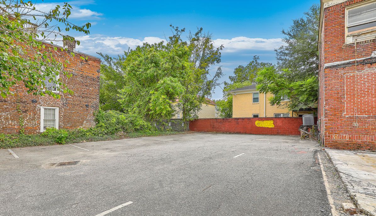 115 Wentworth Street. Vacant brick office building with boarded up windows from the back with parking lot behind to it.