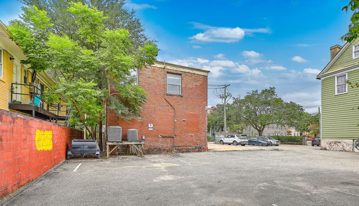 115 Wentworth Street. Vacant brick office building with boarded up windows from the back with parking lot behind to it.