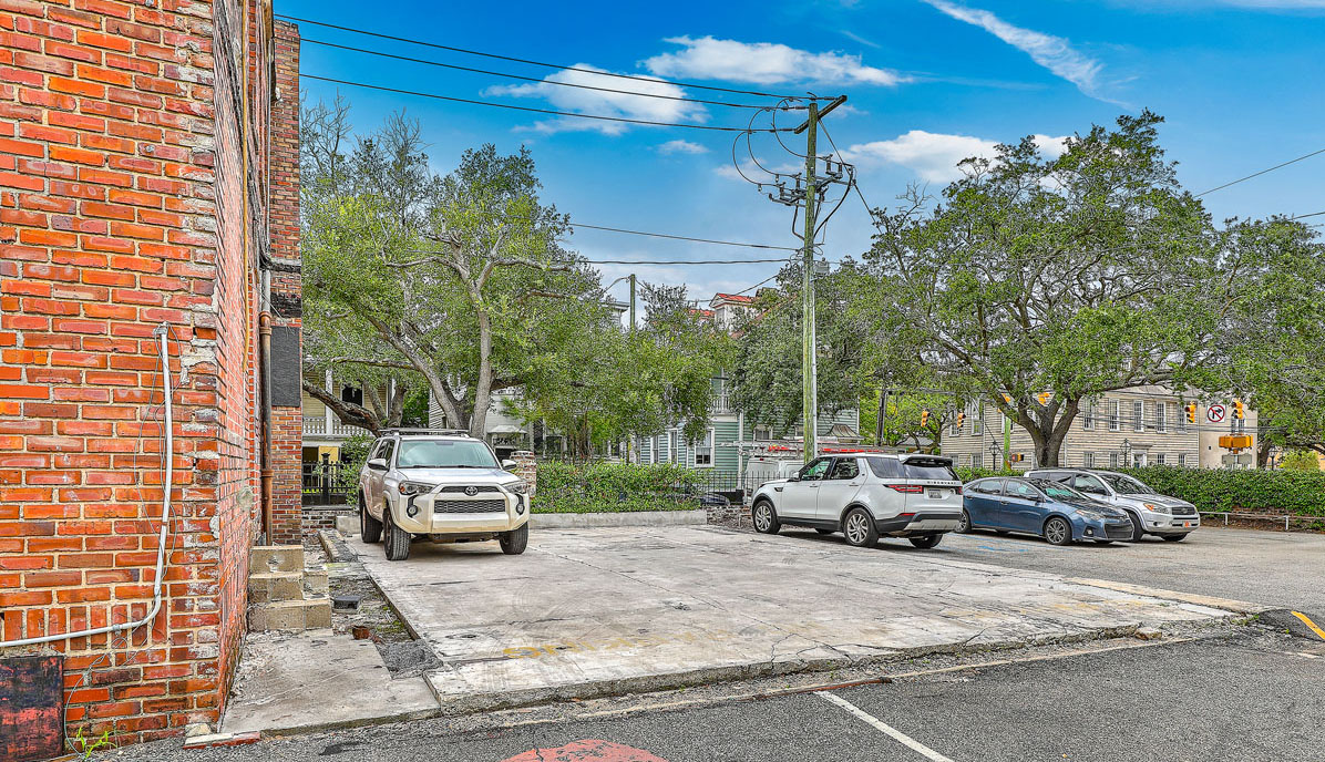 115 Wentworth Street. Vacant brick office building with boarded up windows from the side with parking lot next to it.